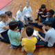 Una decina di bambini seduti in cerchio in palestra